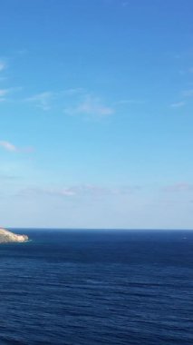 Solunda kayalık bir kıyı şeridi olan açık bir gökyüzü ile açık mavi denizin birleşiminin geniş bir görüntüsü. Yunanistan, Monemvasia yakınlarında yakalandı.