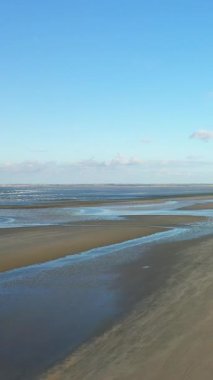 Fransa 'nın Normandiya eyaletindeki Utah Sahili' nde açık mavi gökyüzünün altında sığ gelgit havuzları olan geniş kumlu bir kıyı şeridi. Huzurlu kıyı manzarası seyahat ve doğa kavramları için ideal..