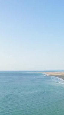 Plage de la Vieille Eglise 'in turkuaz deniz ve açık mavi gökyüzünün altındaki kumlu sahil manzarası. Sakin kıyı manzarası seyahat ve doğa kavramları için mükemmeldir..