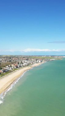 Sword Beach 'in manzaralı manzarası ve Hermanville-sur-Mer, Fransa kıyı şeridi, turkuaz su ve açık mavi gökyüzü altında konut evleri..
