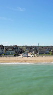 Açık mavi gökyüzü altında Hermanville-sur-Mer, Fransa 'da kumlu kıyı, sakin deniz ve kıyı evleri ile Kılıç Sahili geniş görünüm.