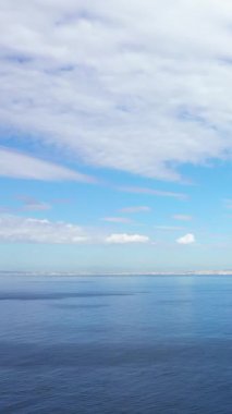 İtalya, Napoli Körfezi üzerinde yumuşak dalgalar ve yumuşak bulutlarla sakin deniz manzarası. Huzurlu mavi su, parlak bir gökyüzünün altındaki uzak ufka kadar uzanıyor..