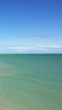 Sakin denizin sakin manzarası Sword Beach, Lion-sur-Mer, Normandiya 'da açık mavi gökyüzü ile buluşuyor. Yumuşak dalgaları ve açık ufku olan sakin sahil manzarası.