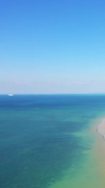 Bernieres-sur-Mer, Normandiya yakınlarındaki Juno Sahili 'nde turkuaz suların ve kumlu kıyı şeridinin havadan perspektifi. Açık mavi gökyüzü ve sakin deniz Sakin bir sahil manzarası oluşturur.