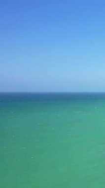 Fransa 'nın Normandiya, Cap de la Hague yakınlarında yakalanan turkuaz okyanus suyunun berrak mavi gökyüzü ile buluşması. Sakin atmosferli minimalist deniz manzarası.