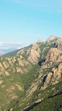 Fransa 'nın Korsika kentindeki engebeli dağların ve yemyeşil vadilerin berrak mavi gökyüzünün altında manzarası. Görkemli doğal arazi seyahat ve macera kavramları için ideal..