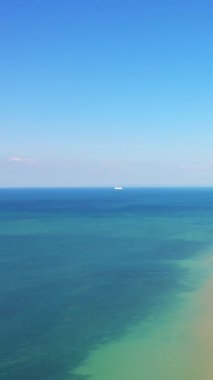 Bernieres-sur-Mer, Normandiya 'daki Juno Sahili' nde berrak mavi bir gökyüzünün altında sakin turkuaz sular uzanıyor. Sakin denizde uzak bir gemi görülebilir..