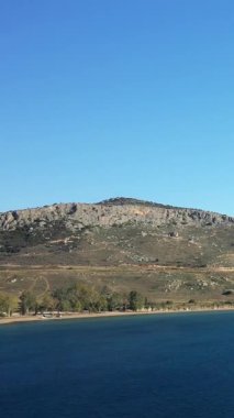 Yunanistan 'ın Nafplio kenti yakınlarındaki Paralia Karathona' da kayalık bir yamaçta açık mavi bir gökyüzü ve sakin bir kıyı şeridi. Doğal manzaralı sakin kıyı manzarası..