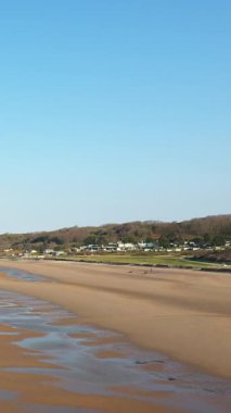 Fransa, Normandiya 'da açık mavi gökyüzü altında ıslak kum ve uzak evlerle Omaha Sahili' nin geniş manzarası.