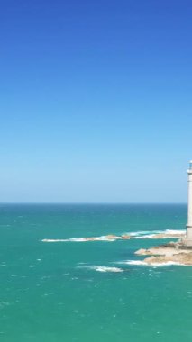 Fransa 'nın Normandiya, Cap de la Hague kentindeki turkuaz suları ve kayalık kıyı şeridi üzerinde açık mavi bir gökyüzü. Huzurlu deniz manzarası ve doğal kıyı güzelliği.