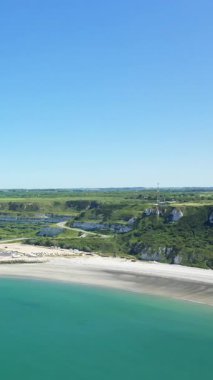 Açık mavi gökyüzünün altında Le Havre, Fransa yakınlarındaki manzaralı sahil uçurumları, kumlu plaj ve turkuaz deniz manzarası. Yeşillik ve dolambaçlı yollar resimli manzarayı tamamlıyor..
