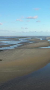 Utah Beach, Fransa 'da açık mavi bir gökyüzünün altında sığ su kanalları olan geniş kumlu gelgit düzlükleri. Huzurlu kıyı manzarası doğa ve seyahat kavramları için ideal..