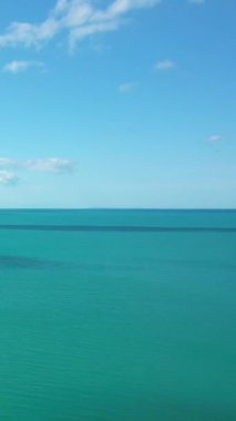 Turkuaz deniz suyunun berrak mavi gökyüzü ile buluşmasının huzurlu manzarası, birkaç dağınık bulut, Peschici, İtalya 'da yakalandı..