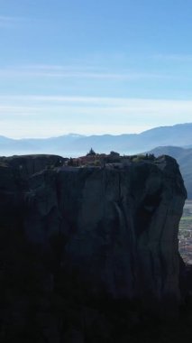 Yunanistan 'ın Meteora kentinde yükselen bir kaya oluşumuna tünemiş tarihi bir manastırın dramatik manzarası..