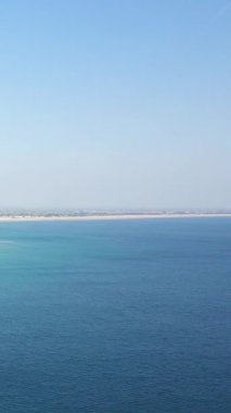 Berrak bir gökyüzünün altında, Fransa 'nın Plage de la Potiniere şehrinde kumlu bir kıyı şeridi bulunan sakin mavi okyanus sularının geniş manzarası..