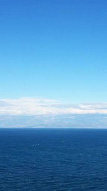 Yunanistan 'ın Koroni kenti yakınlarında uzak bir sıradağla berrak gökyüzünün altındaki derin mavi deniz manzarası. Huzurlu ve geniş doğal manzara arka plan veya seyahat kavramları için idealdir..