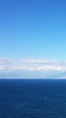 Açık gökyüzünün altında sakin mavi bir deniz, ufukta uzak dağlar, Yunanistan 'ın Koroni kenti yakınlarında ele geçirildi. Huzurlu deniz manzarası seyahat ve doğa kavramları için idealdir.