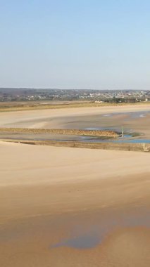 Geniş kumlu plaj gelgit havuzları ve Grande Plage de Barneville, Normandiya, Fransa 'da açık mavi gökyüzü altında dalgalanan sular..