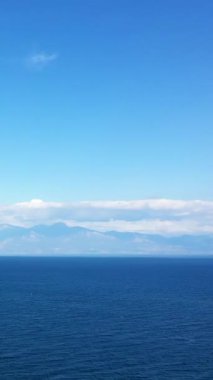 Yunanistan 'ın Koroni kenti yakınlarında, berrak bir gökyüzü altında derin mavi su ve uzak dağlarla sakin deniz manzarası.
