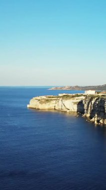 Dik kireçtaşı kayalıkları açık bir gökyüzünün altında Fransa 'nın Korsika kentindeki Bonifacio kıyısı boyunca Akdeniz' in üzerinde yükseliyor..