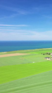 Berrak bir yaz gününde Normandiya kayalıkları boyunca uzanan yemyeşil çayırların havadan görünüşü.