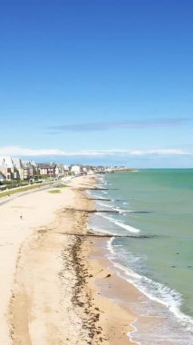 Açık güneşli bir günde Lion-sur-Mer, Fransa 'daki Sword Beach' in kumlu kıyı şeridi ve turkuaz sularının hava manzarası.