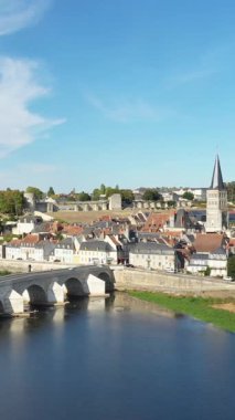 Loire Nehri 'ni geçen ikonik taş köprüsü ve açık mavi gökyüzü altında geleneksel Fransız mimarisi ile La Charite-sur-Loire manzarası..