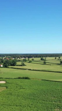Saint-Germain-Chassenay, Fransa 'da açık mavi gökyüzü altındaki yeşil tarlaların ve köy binalarının havadan görüntüsü. Tarımsal arazisi ve dağınık evleri olan huzurlu bir kır manzarası..