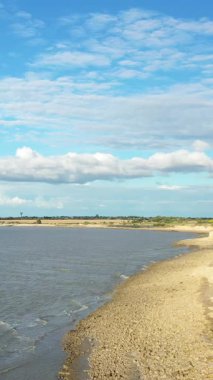 Lao kırsalında mavi bir gökyüzünün altında kayalık kıyısı olan sakin bir nehir kıyısına geniş bir manzara. Açık su ve bulutlu doğal kırsal manzara.