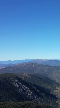 Açık mavi gökyüzünün altında, Fransız kırsalının karakteristik bir özelliği olan rüzgar türbinleri olan yeşil tepelerin manzarası. Manzara sükunet ve sürdürülebilir enerji taşır..