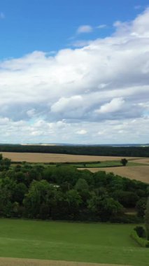 Fransa 'nın Varzy şehrinde, Cuncy les Varzy' de parçalı bulutlu bir gökyüzünün altında yeşil tarlalar, ağaçlar ve geniş tarım arazisi manzarası..