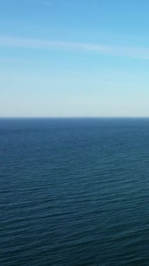 Sakin deniz manzarası, berrak mavi bir gökyüzünün altında, Normandiya uçurumlarının kıyılarından esinlenilmiş, yumuşak dalgalar..