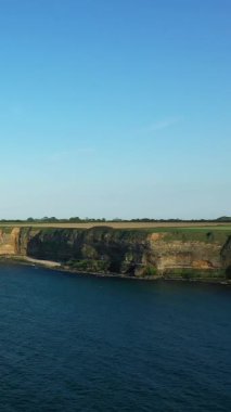Normandiya 'nın dramatik uçurumları açık bir günde sakin mavi denizin üzerinde yükselir, ufuk boyunca uzanan tarlalar. Doğal manzara yumuşak güneş ışığıyla yıkanır..