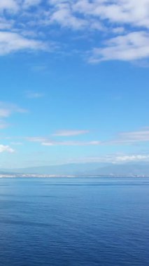 İtalya 'nın Napoli Körfezi' nde bulutlu bir gökyüzünün altında berrak mavi suyu ve uzak bir kıyı şeridi olan sakin bir deniz manzarası..