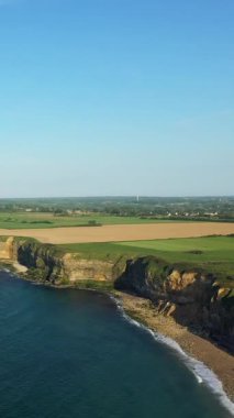 Denizle buluşan dramatik Normandiya uçurumlarının havadan görünüşü, yeşil alanlar ve arka planda açık mavi gökyüzü. Kuzey Fransa 'da sakin kıyı manzarası.