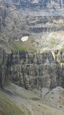 Küçük çağlayan şelaleleri olan sarp kayalıklar ve Fransız Pireneleri Cirque de Gavarnie 'de kar parçaları. Engebeli dokuları ve dikey kaya yüzeyleriyle dramatik doğal manzara..