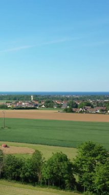 Yeşil tarlaların manzarası, küçük bir köy ve açık mavi gökyüzünün altında Normandiya, Fransa 'daki Hillman Bataryaları yakınlarında.