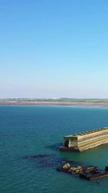 Asnelles, Normandiya, Fransa yakınlarındaki Gold Beach 'in berrak mavi sularındaki beton bir liman yapısının havadan görüntüsü..