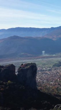 Dramatik kaya oluşumlarının manzaralı görüntüsü ve Yunanistan 'ın Meteora Vadisi' ne kurulmuş bir kasaba, açık bir gökyüzünün altında dağlar..