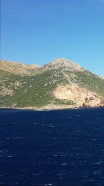 Yunanistan 'ın Porto Kagio kentinde berrak bir gökyüzü altında engebeli bir yamacın derin mavi sularla buluşmasının manzarası. Doğal kıyı manzarası seyahat ve doğa kavramları için ideal..