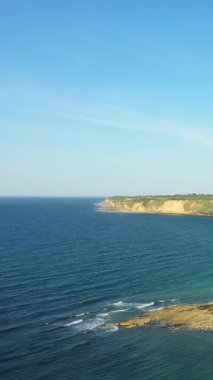 Dramatik uçurumlar ve Pointe du Hoc, Normandiya, Fransa 'daki açık bir gökyüzünün altındaki mavi deniz manzarası. Engebeli kıyı şeridi ve yumuşak dalgalar manzaralı doğal bir manzara yaratır..