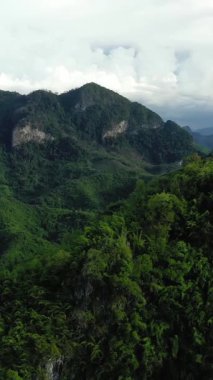 Nong Khiaw, Laos çevresindeki yoğun yeşil dağların ve dramatik bulutların havadan görünüşü. Bereketli tropikal orman kasvetli bir gökyüzünün altındaki engebeli araziyi kaplıyor..
