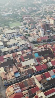 Battambang, Kamboçya 'daki kentsel binaların ve çatıların yüksek açılı görüntüsü, ticari ve konut yapılarının karışımı ile yoğun bir şehir manzarası sergiliyor..