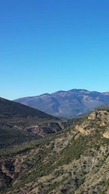 Yunanistan 'daki tarihi Osios Loukas Manastırı yakınlarındaki engebeli dağların ve açık mavi gökyüzünün manzarası. Yeşil bitki örtüsü ve kayalık yamaçlı doğal arazi.