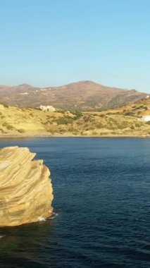 Yunanistan 'ın Girit plajında, arka planda dağlarla birlikte altın güneş ışığı altında dramatik kayalık kayalıklar ve berrak mavi deniz..