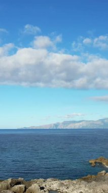 Berrak mavi suyu, uzak dağları olan sakin bir deniz manzarası ve Maratea, İtalya yakınlarında yakalanan parçalı bulutlu bir gökyüzü..