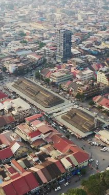 Kamboçya 'nın hareketli Battambang pazar bölgesinin renkli çatıları ve işlek caddeleri ile yoğun şehir manzarasını gösteren yüksek açılı hava görüntüsü..