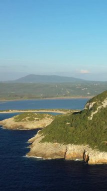Engebeli sahil uçurumlarının havadan görünüşü, yemyeşil tepeler ve Yunanistan 'daki Chateau de Navarino yakınlarında sakin bir lagün. Açık mavi gökyüzü ve manzaralı manzara huzurlu bir Akdeniz atmosferi yaratır.
