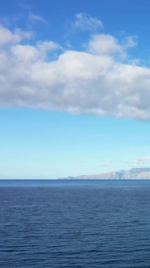 Mavi gökyüzünün altında uzak dağları olan sakin deniz manzarası, İtalya, Maratea yakınlarında ele geçirildi..