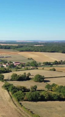 Fransa 'nın Cuncy les Varzy şehrinde açık mavi gökyüzü altında yama arazileri, tarım arazileri ve dağınık ağaçların hava manzarası. Tarım arazisi ve uzak ormanları olan sakin bir kırsal alan..